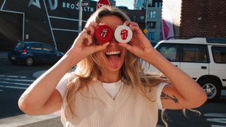 A woman holding two little Cruiser speakers over her eyes and making a face