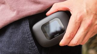 Cleer Arc 3's smart-screen case, held in a hand, about to be put into a pocket