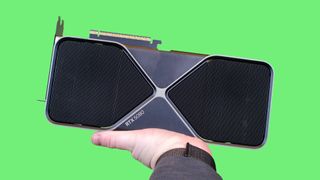 A masculine hand holding up an Nvidia GeForce RTX 5080 against a green background