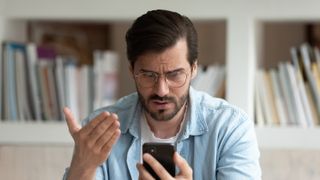 A man looks disgruntled at his phone screen