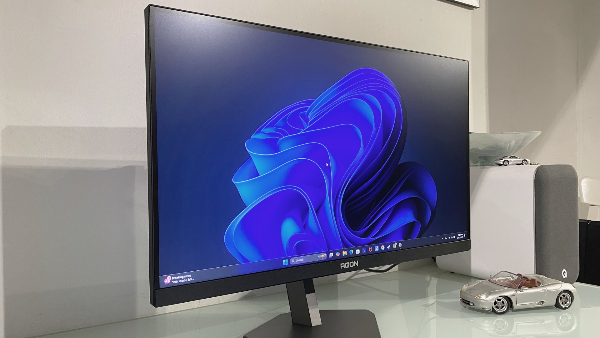 AOC Agon Pro AG276FK gaming monitor tilted slightly to the side, showing the Windows 11 desktop screen