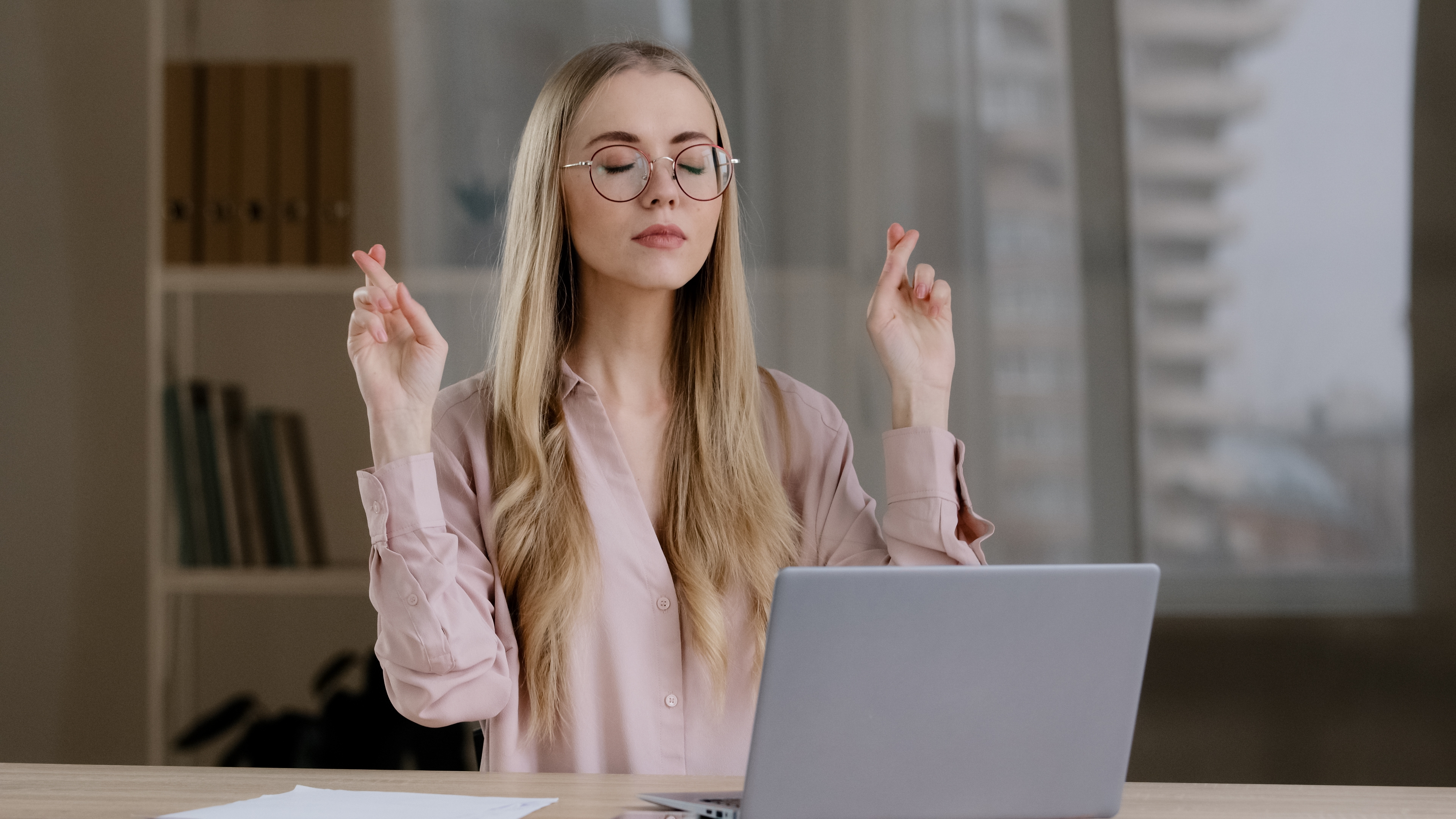 woman using laptop hoping for good luck with her fingers crossed