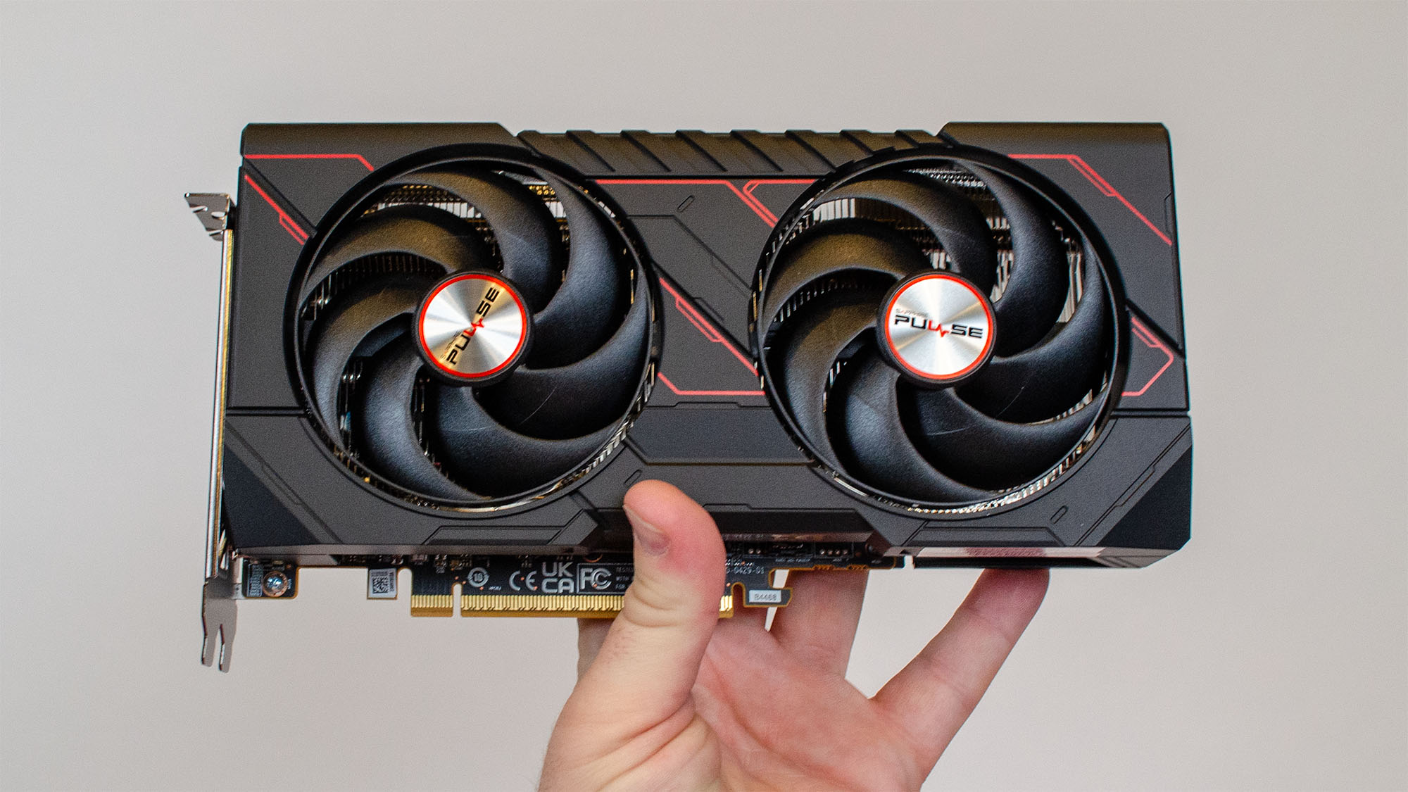 A masculine hand holding an AMD Radeon RX 9060 XT