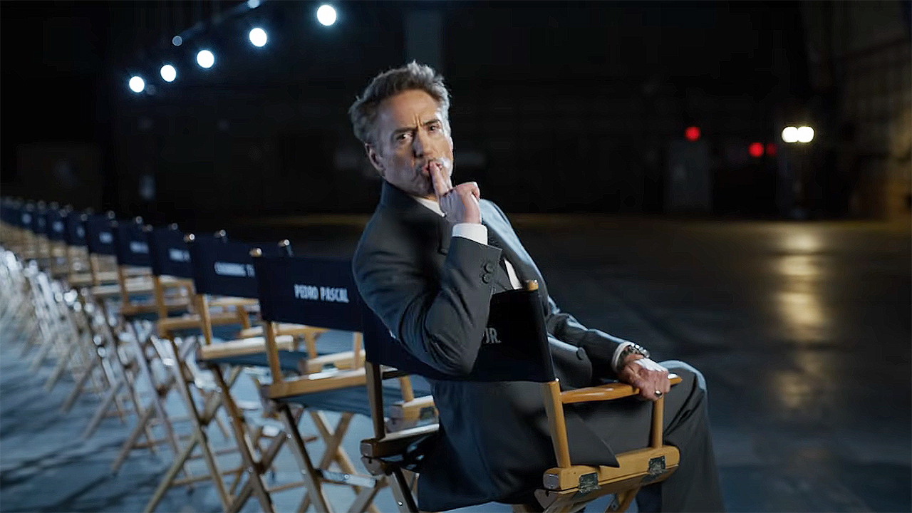 Robert Downey Jr sitting in a chair and holding a finger to his lips during Marvel&#039;s Avengers: Doomsday cast reveal