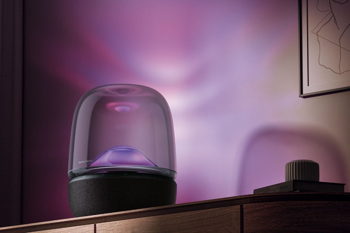 Harman Kardon Aura Studio 5, on top of a sideboard, emitting purple light onto the walls