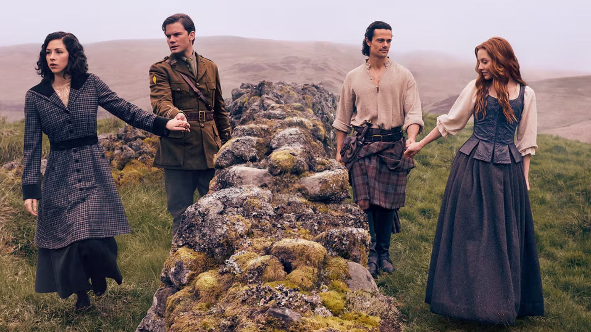 Two couples take each other by the hand either side of a small stone wall