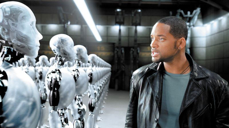 Will Smith stands looking at a line of robots in a still from I, Robot
