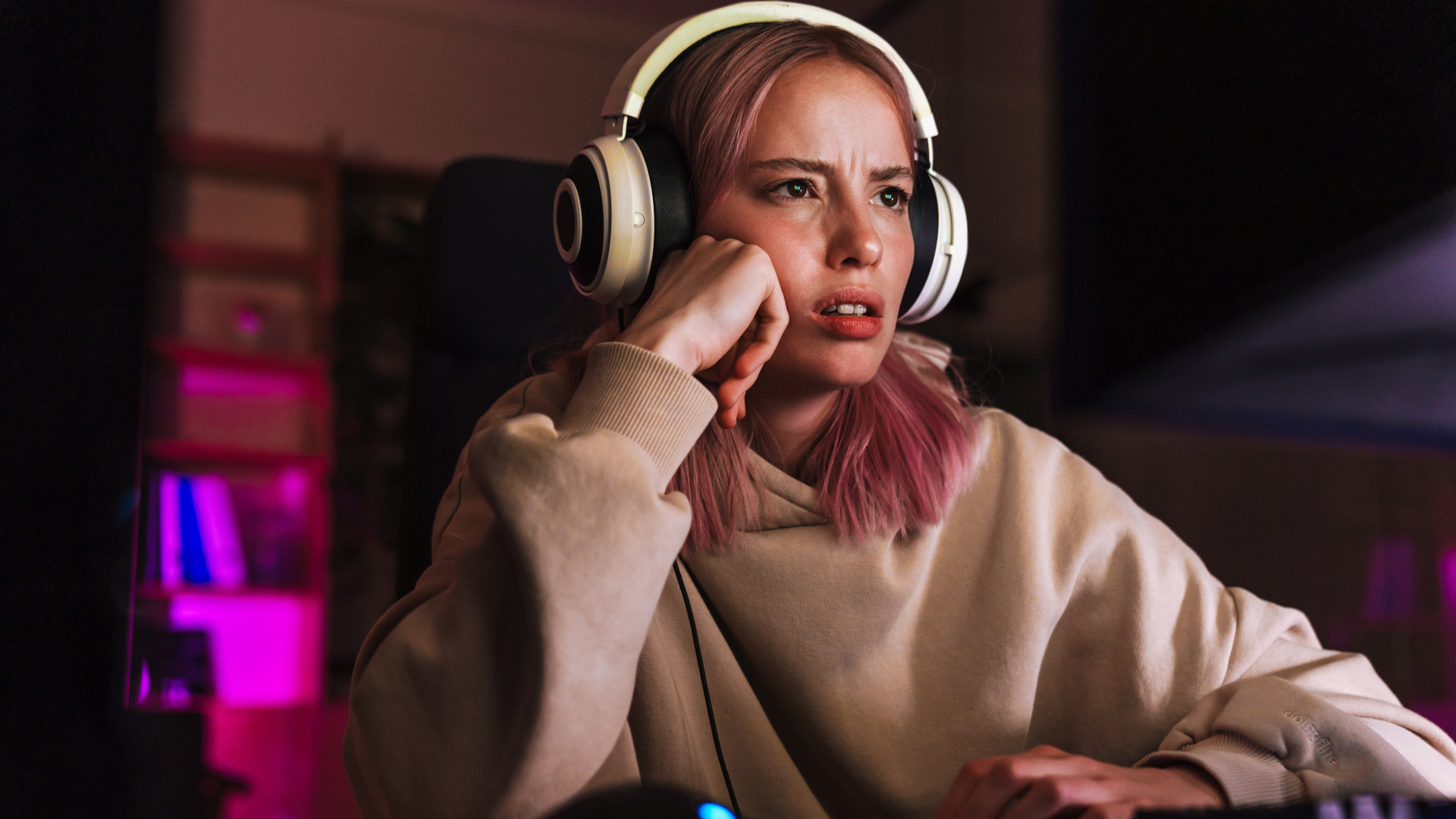 A frustrated looking girl using a gaming PC