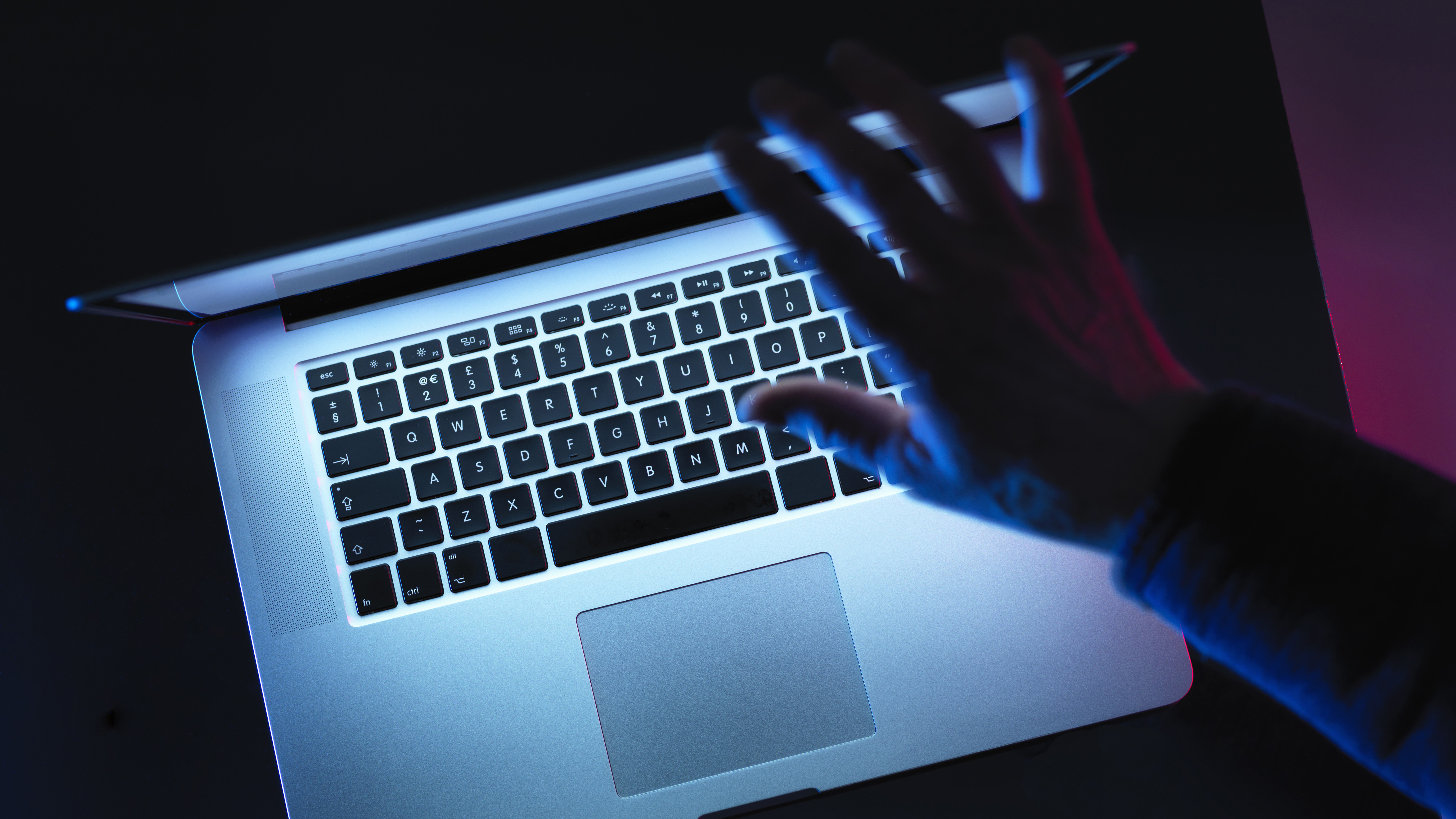A hand closing a laptop screen in the dark