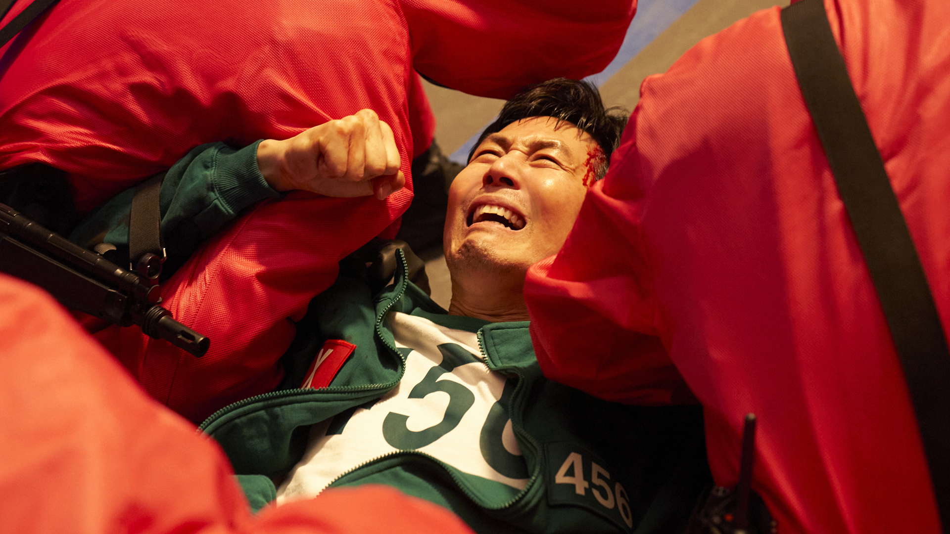 Gi-hun crying as he's held down by pink jumpsuit-wearing soldiers in Squid Game season 3