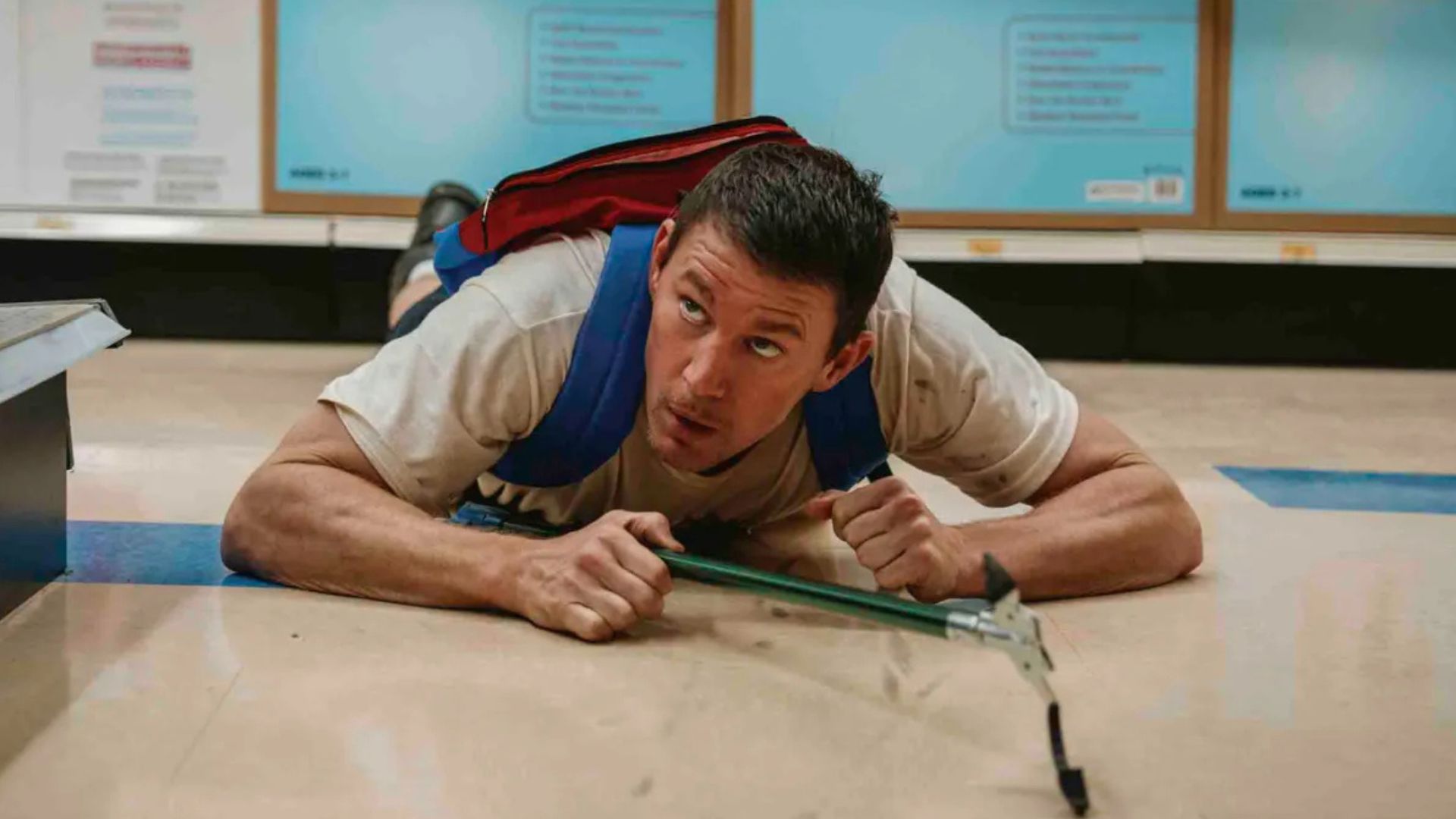 Channing Tatum lies on the floor looking upwards with a grabber in his left hand