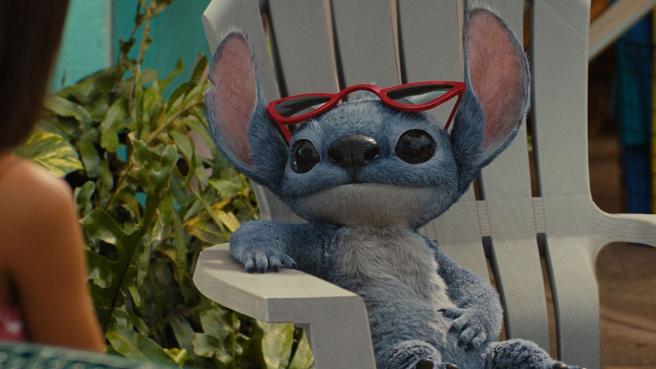 Lilo sitting on a white chair with red sunglasses perched on his head in Disney's Lilo &amp;amp; Stitch live-action remake