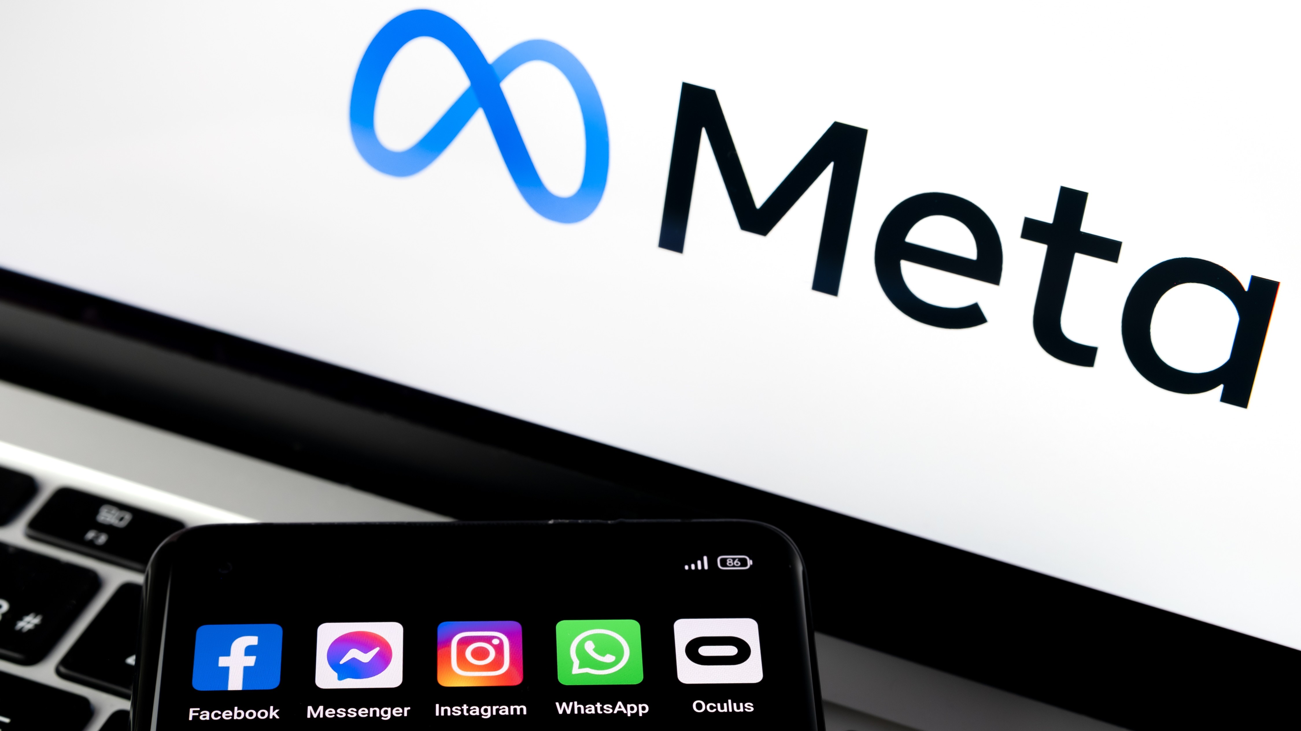 Silhouette of smartphone with Facebook, Messenger, WhatsApp, Instagram, Oculus apps and blurred META logo on background