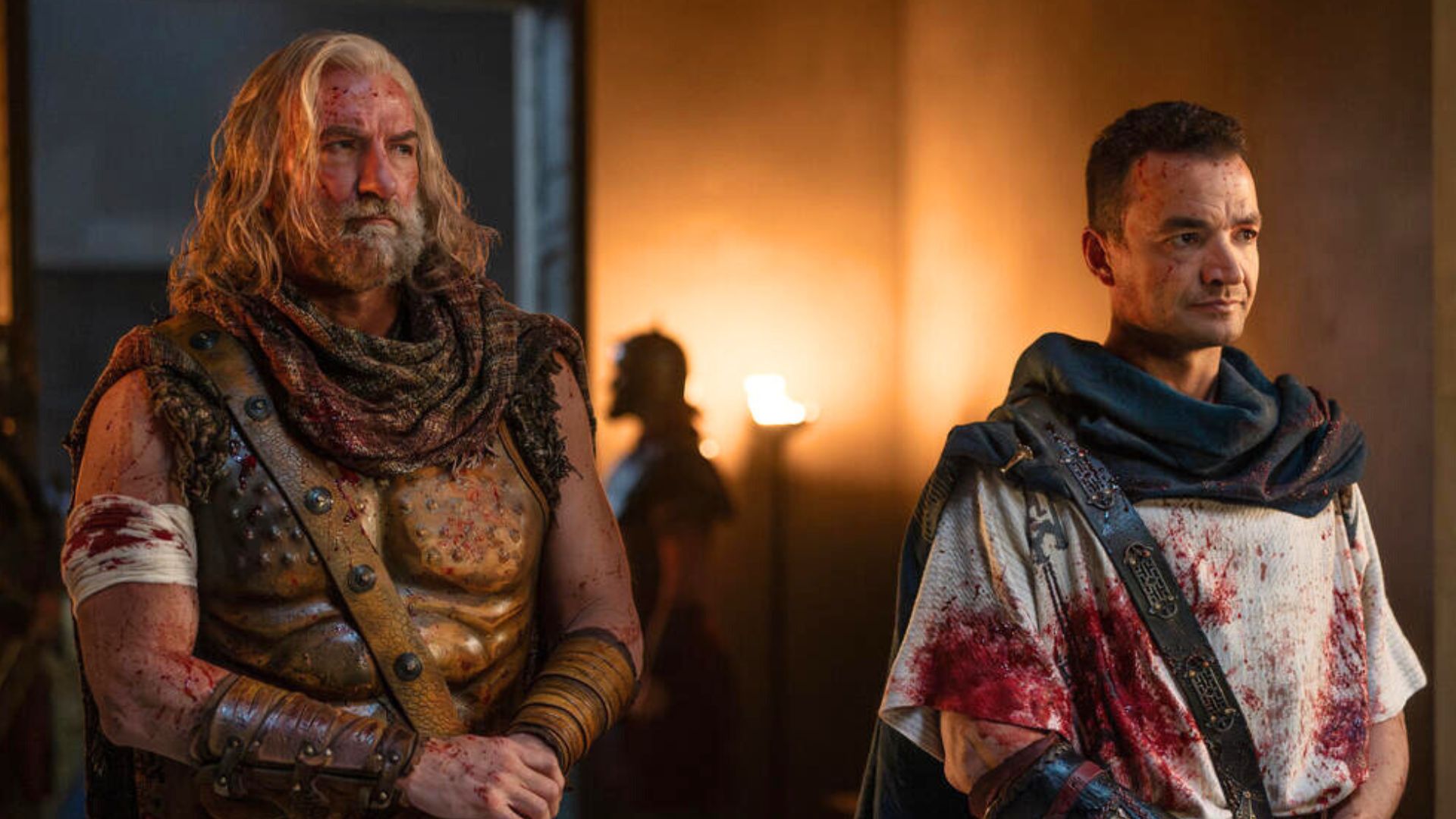Korris and Ashur stand next to each other covered in blood