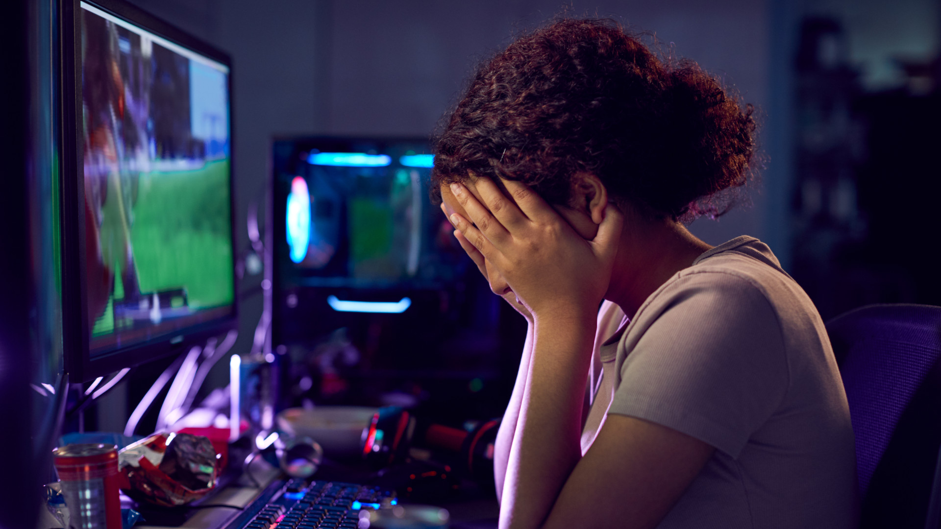 Upset gamer sat at her PC with head in her hands