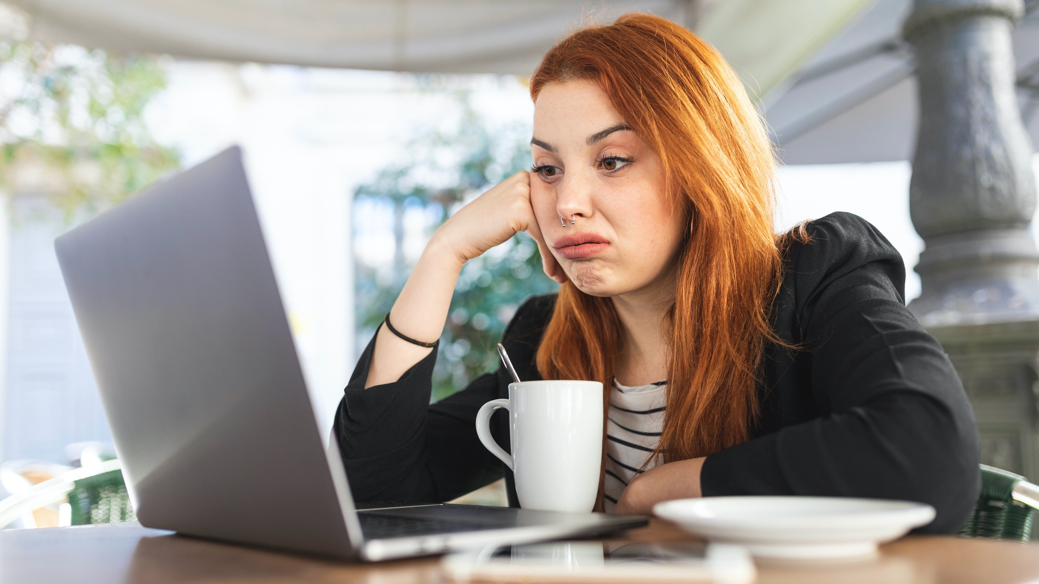Young woman using Windows 11 laptop, looking annoyed