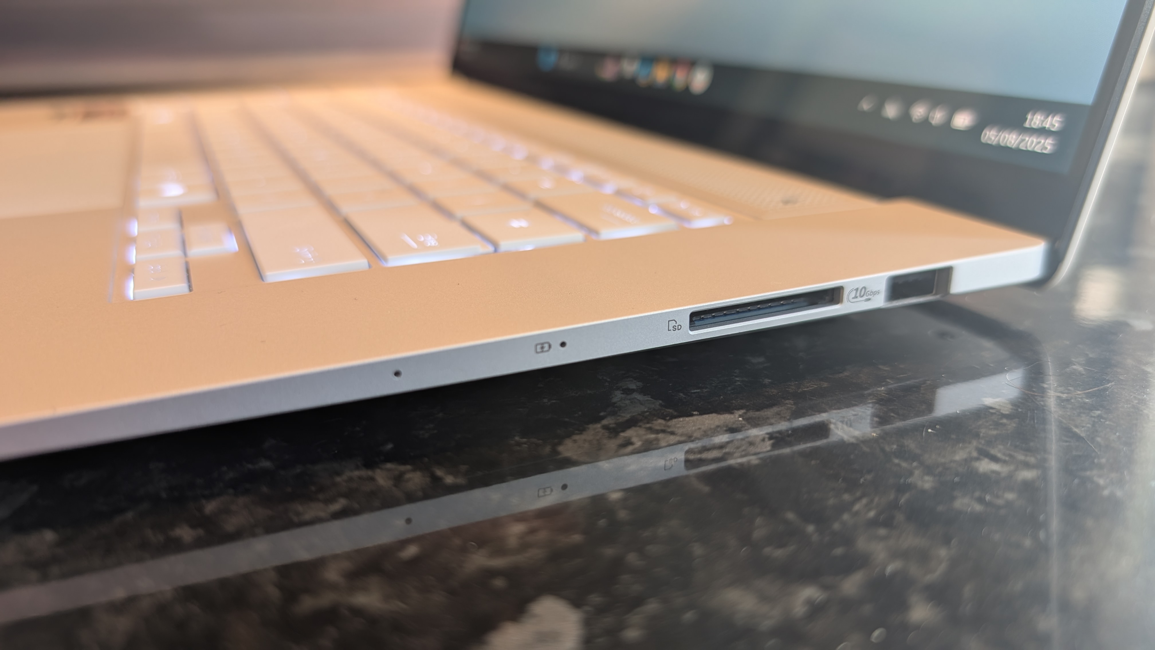 Asus Zenbook S 16 photographed on a dark marble surface with potted plants in the background