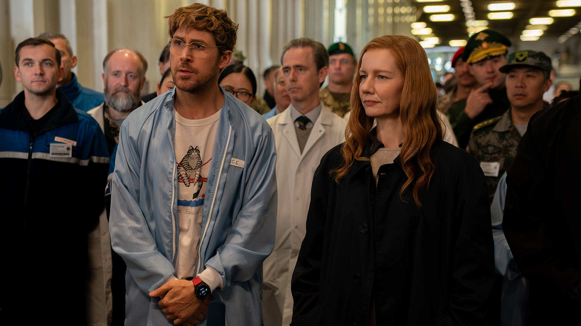 Ryland Grace and Eva Stratt watching an experiment with a group of people in Project Hail Mary