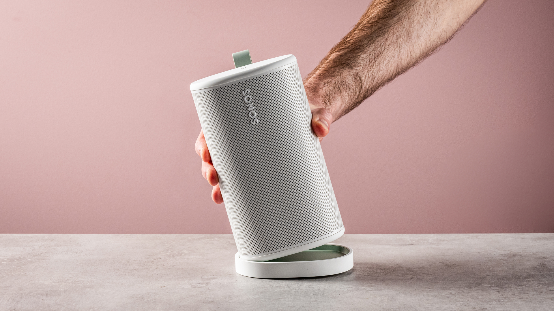 The Sonos Play speaker being removed from its charging cradle by a man's hand