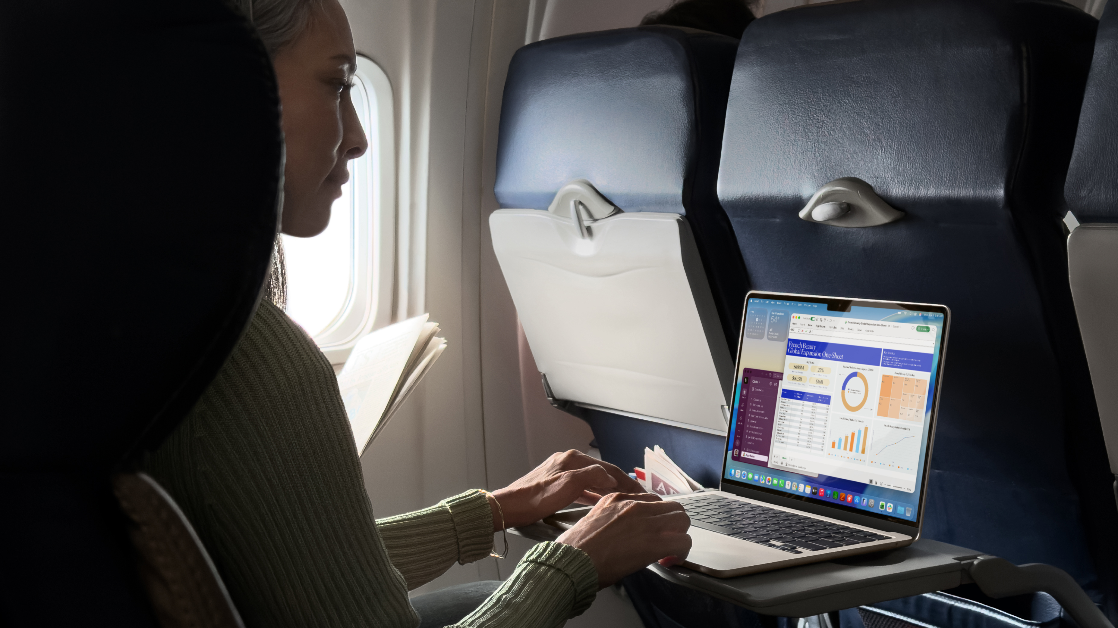 A woman typing on a MacBook Air M5 on a plane