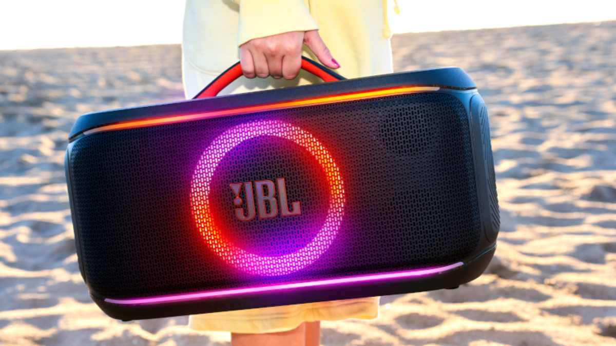 The JBL PartyBox On the Go 2 Plus being held by a woman on the beach.