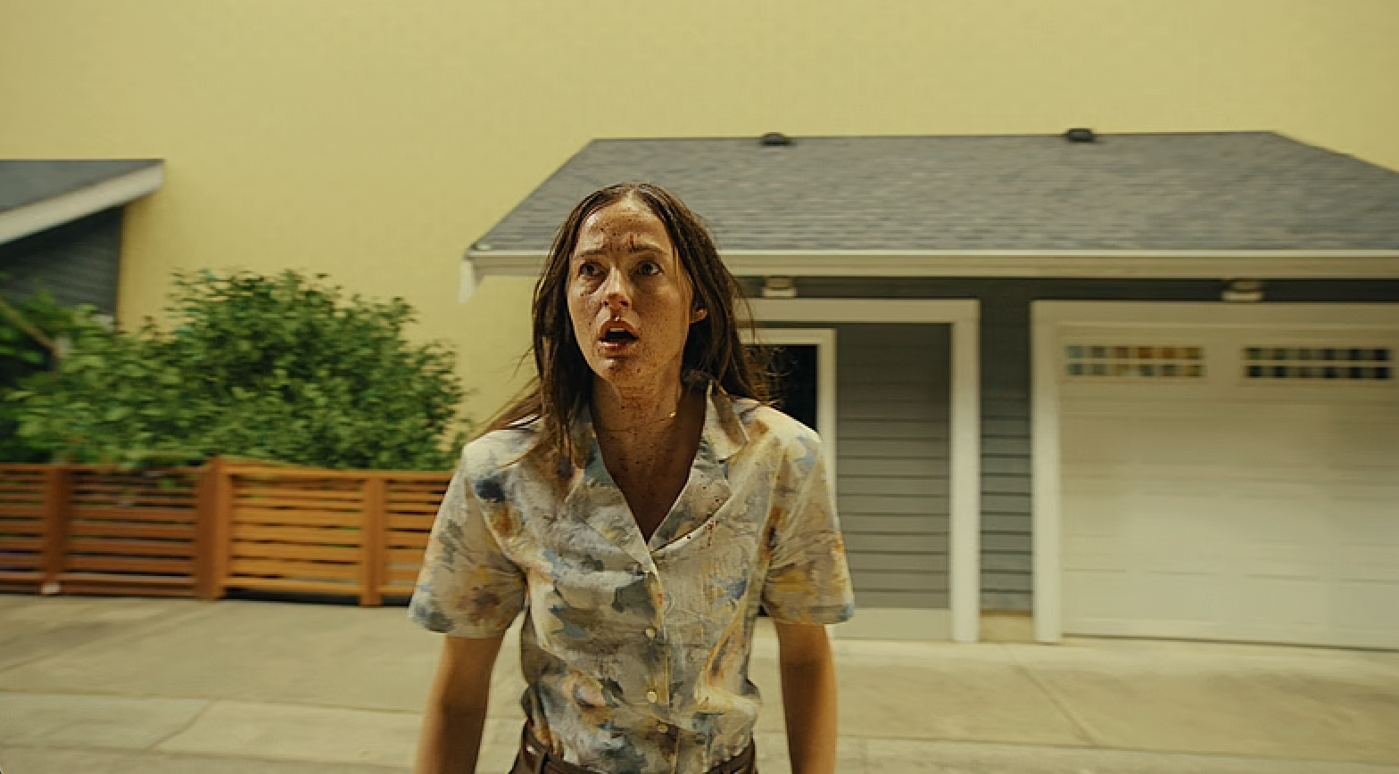 Renate Reinsve in Backrooms, standing in front of houses with a sickly yellow background behind them