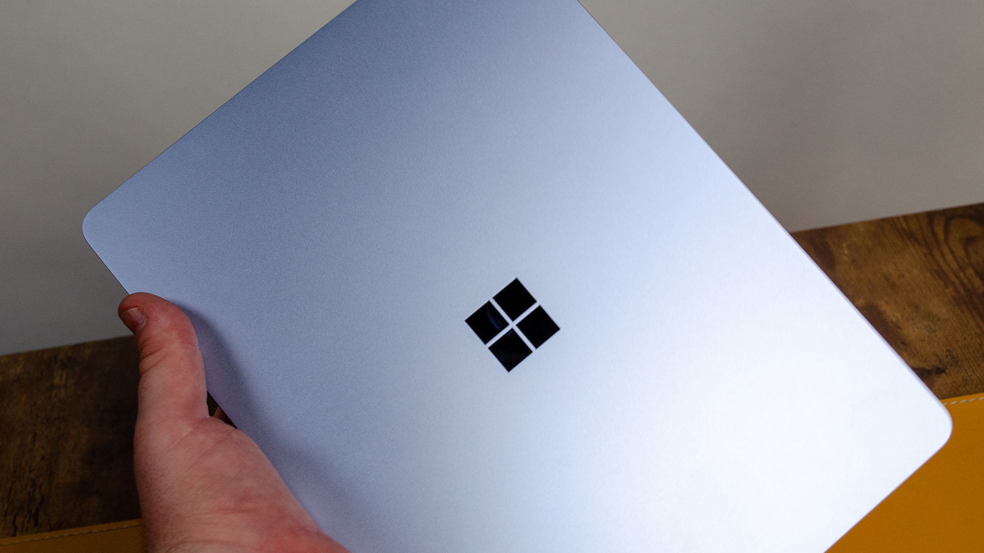 A masculine hand holding the Microsoft Surface Laptop 13-inch