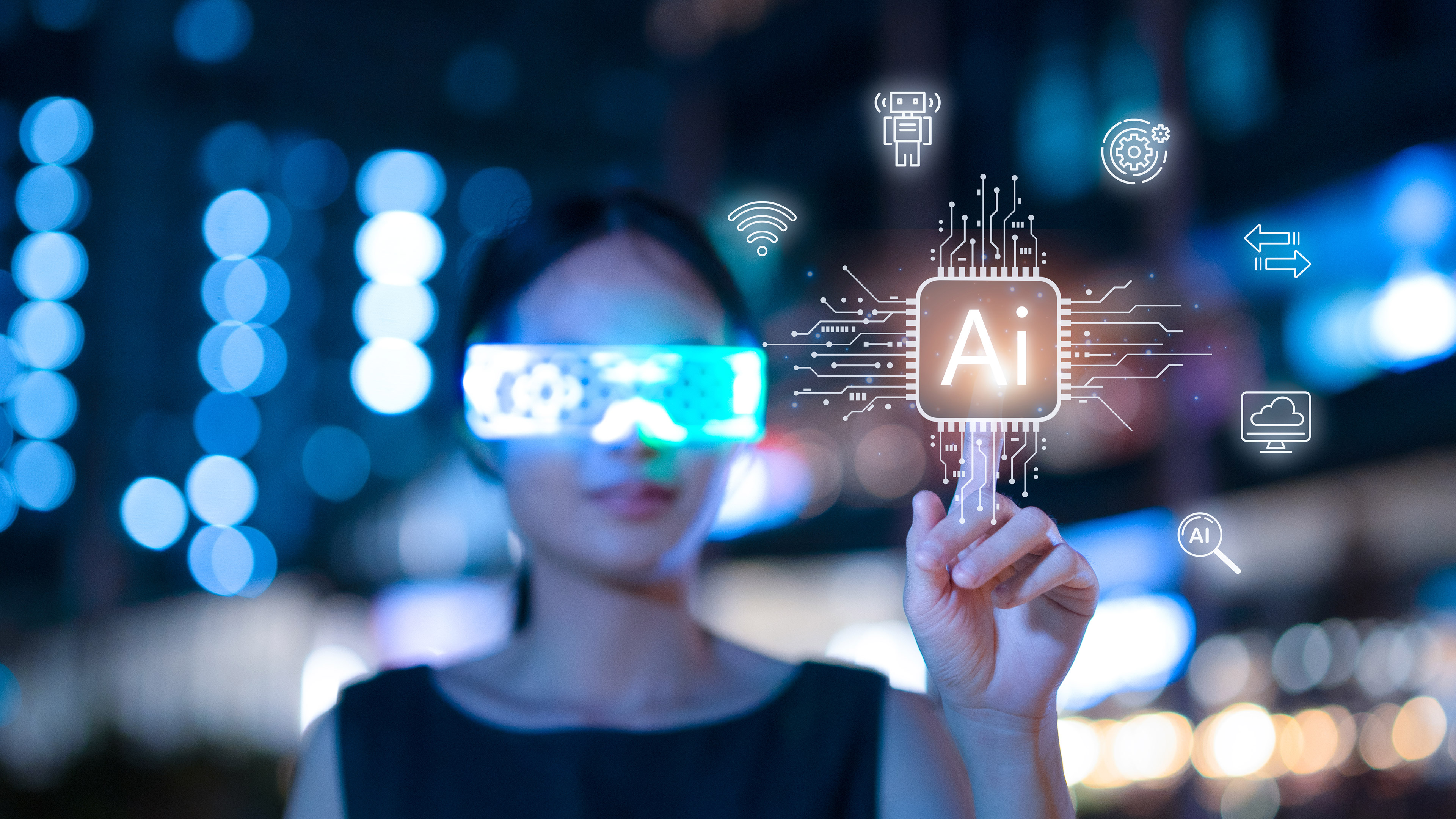 A woman out of focus in the background touches the word AI, lit up in glowing yellow light, in the foreground. The woman is wearing smart glasses