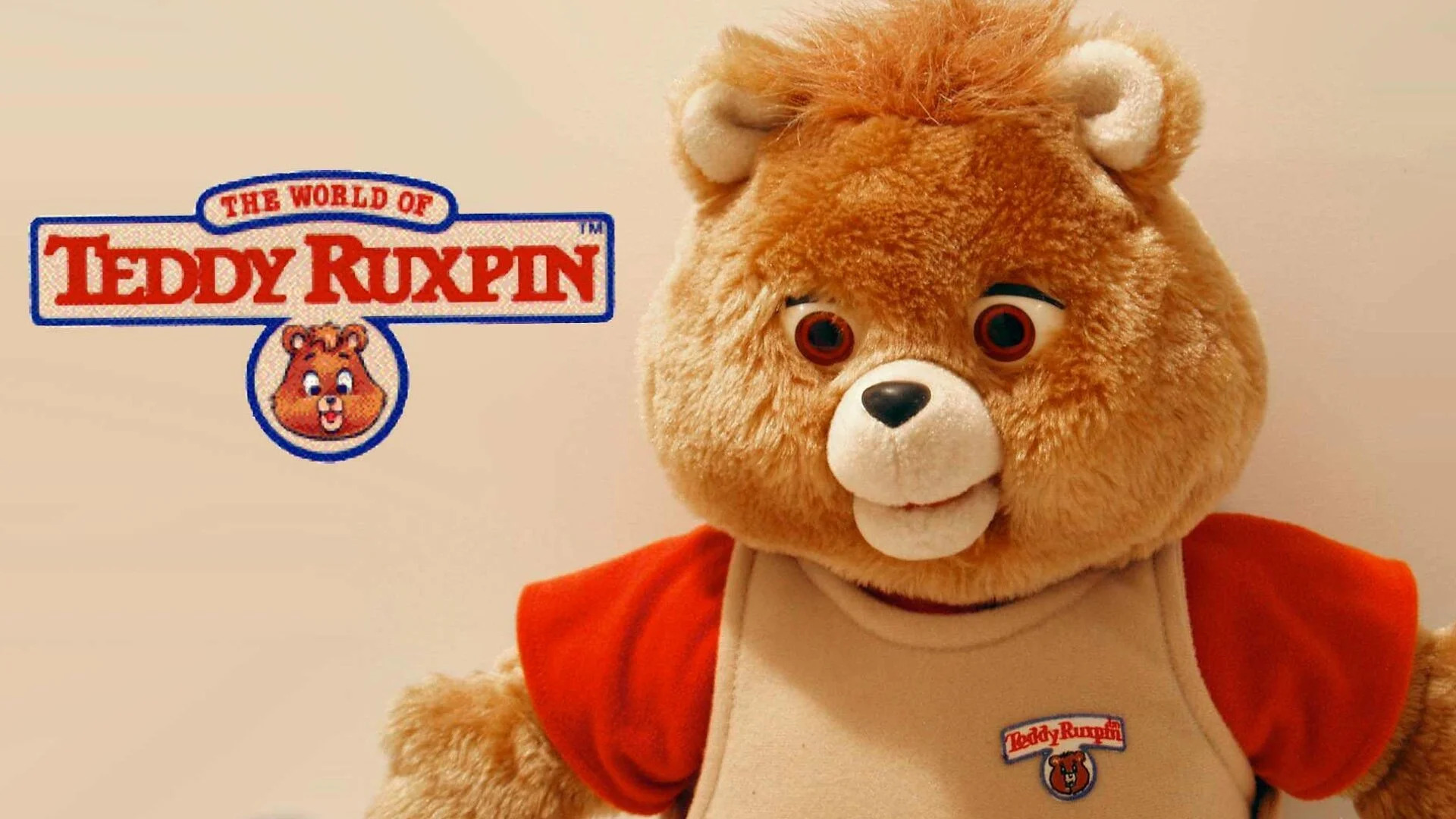 A screenshot of a Teddy Ruxpin toy next to its logo