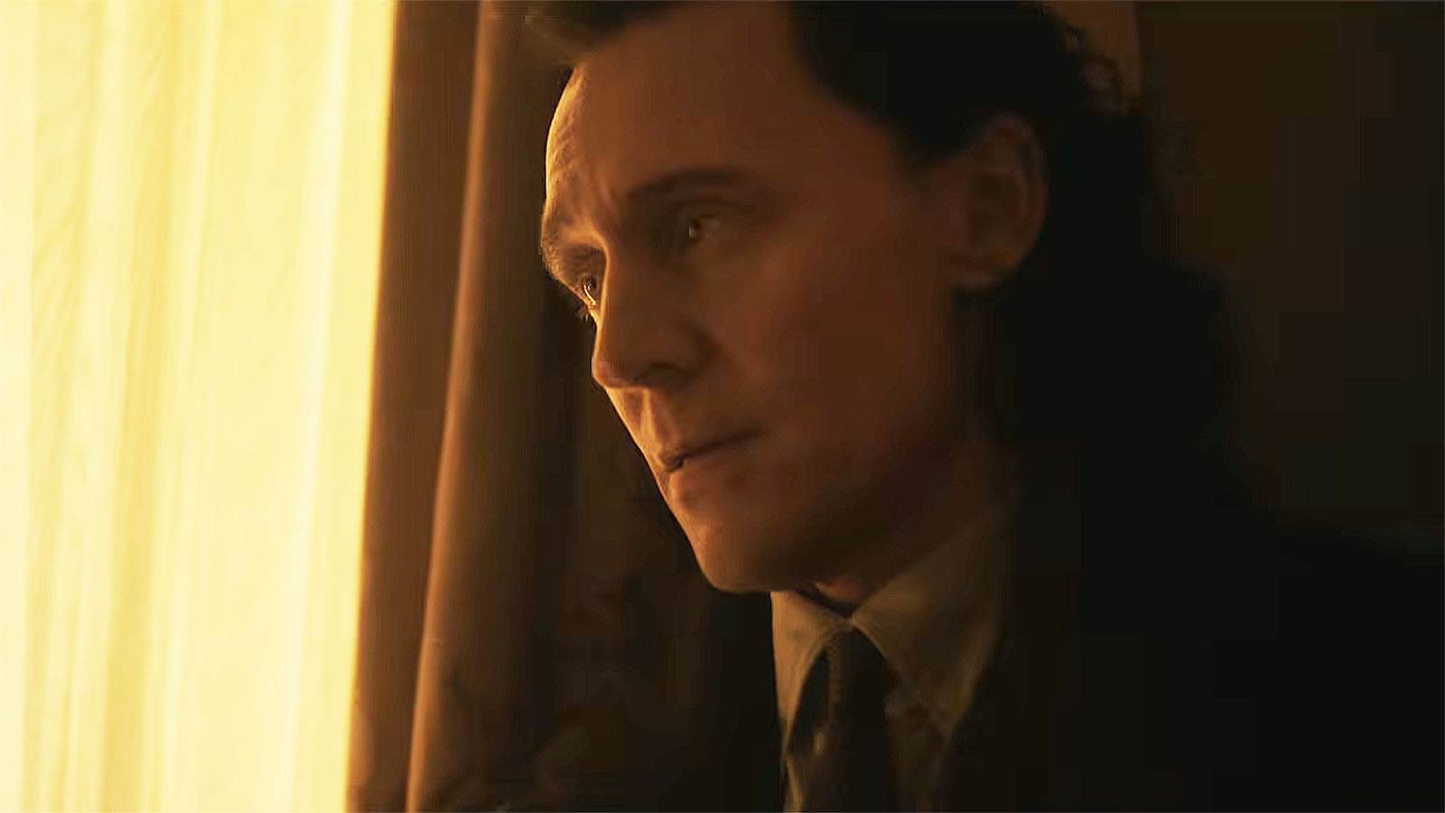 Loki leaning up against a window with a yellow curtain across it in Avengers: Doomsday