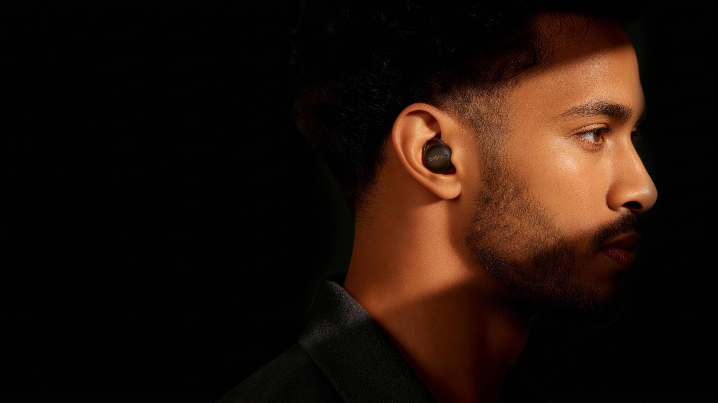 The Belkin SoundForm Isolate Buds in a shadowy man's ear.